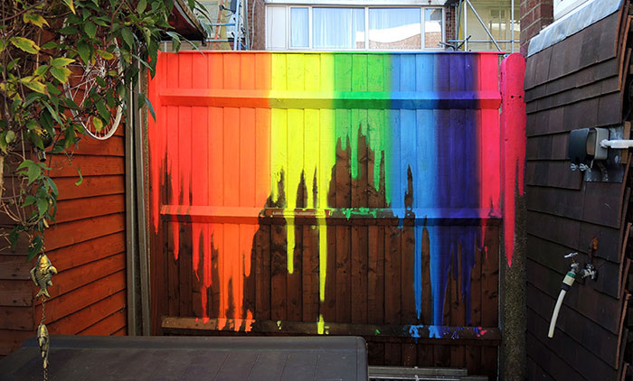 dripping rainbow neon street art mural painted on a garden fence