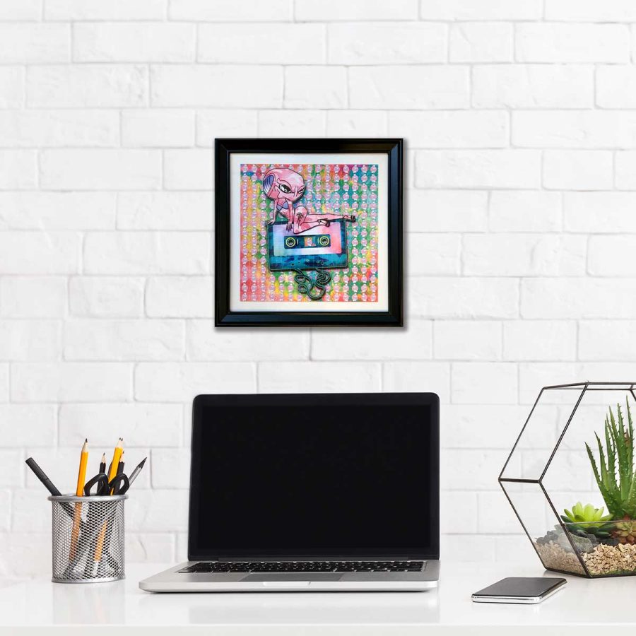 photo of a framed lsd blotter acid art print featuring psychedelic rainbow colours and an alien posing on top of a audio cassette tape trippy gift