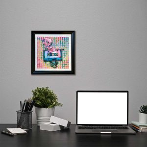 photo of a framed lsd blotter acid art next to a desk with a laptop alternative home and office decoration