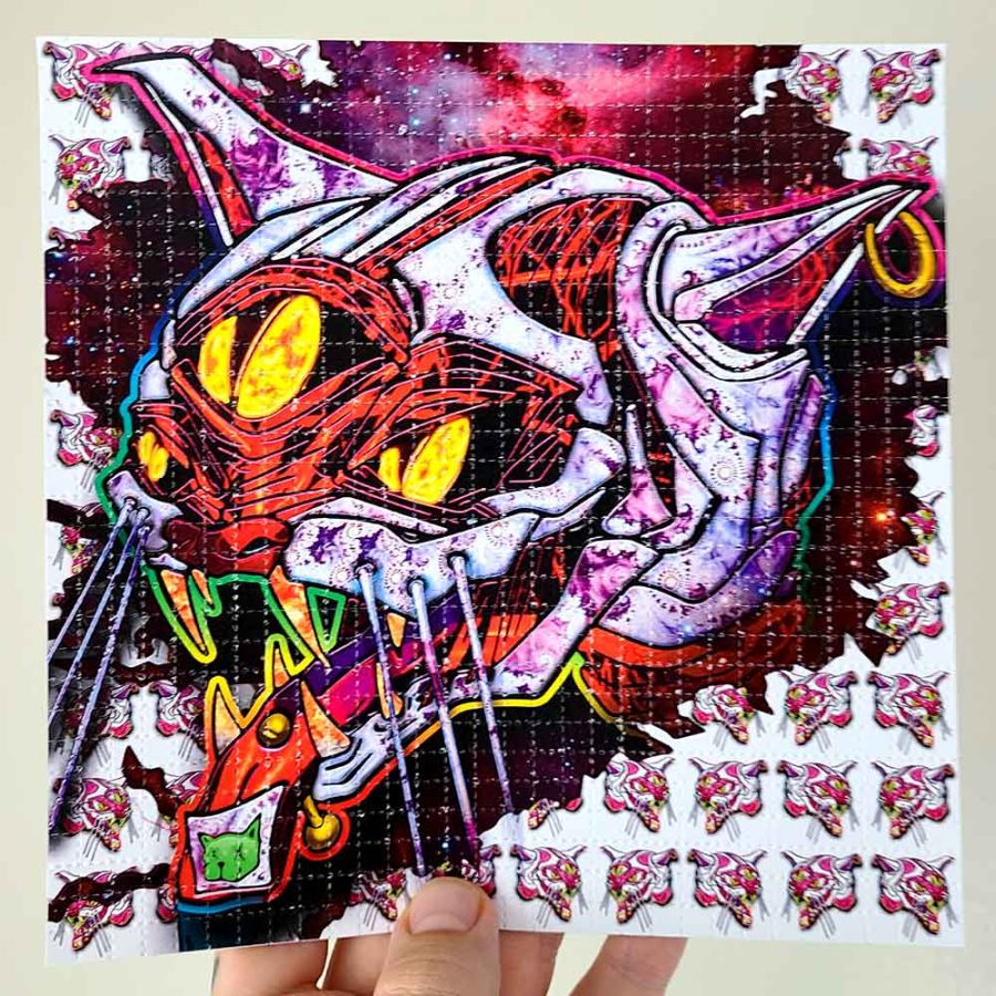 photo of a hand holding LSD blotter acid art print featuring a cat with an acid tab on its tongue