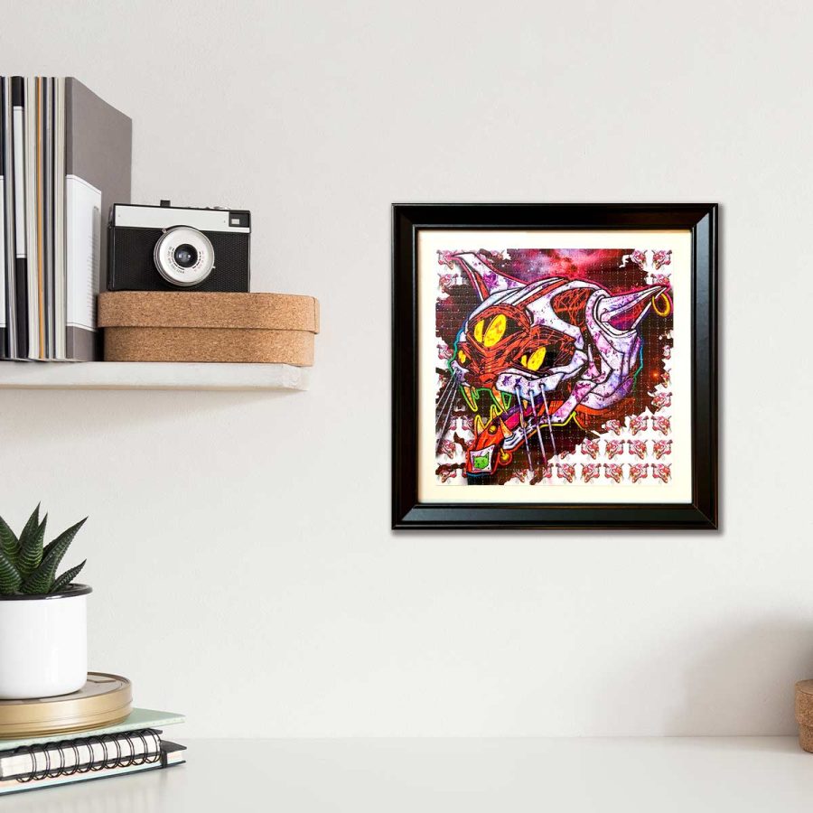 photo of a framed LSD blotter acid art print featuring a cat with an acid tab on its tongue next to a wine bottle