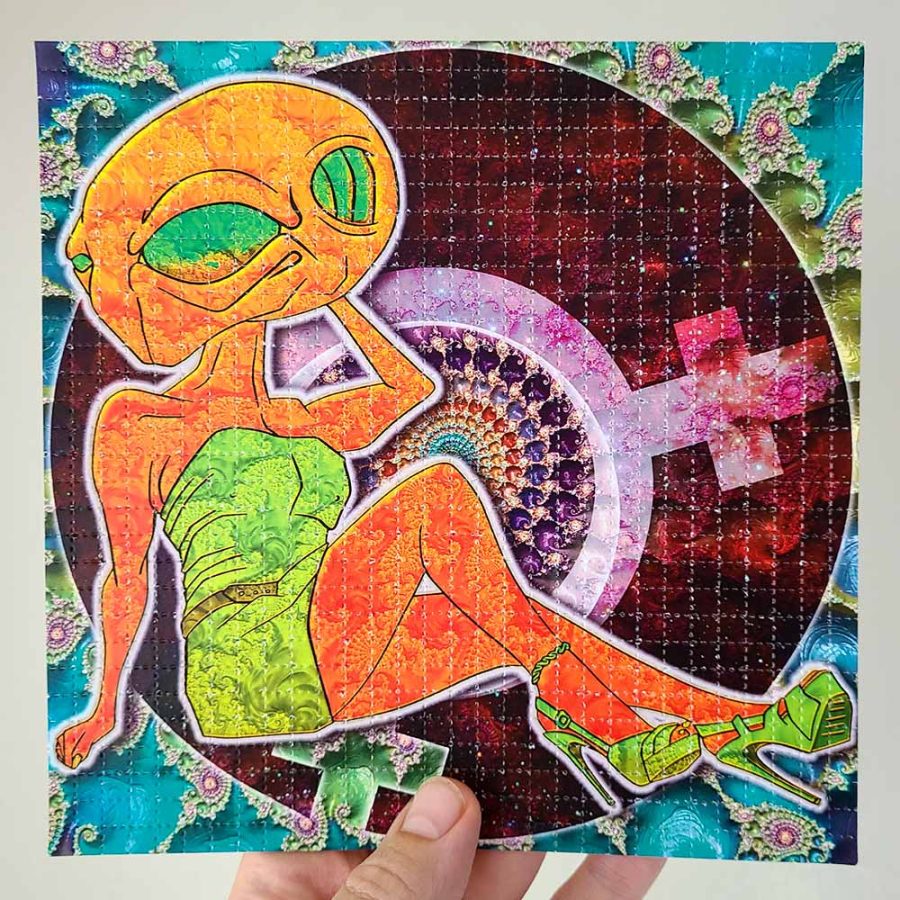 photo of a hand holding alien themed lsd blotter art gift featuring psychedelic colours and fractals