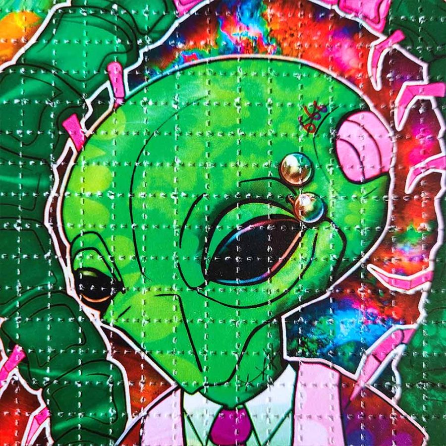 close up photo of lsd blotter art print featuring an alien wearing a suit with pierced eyebrow
