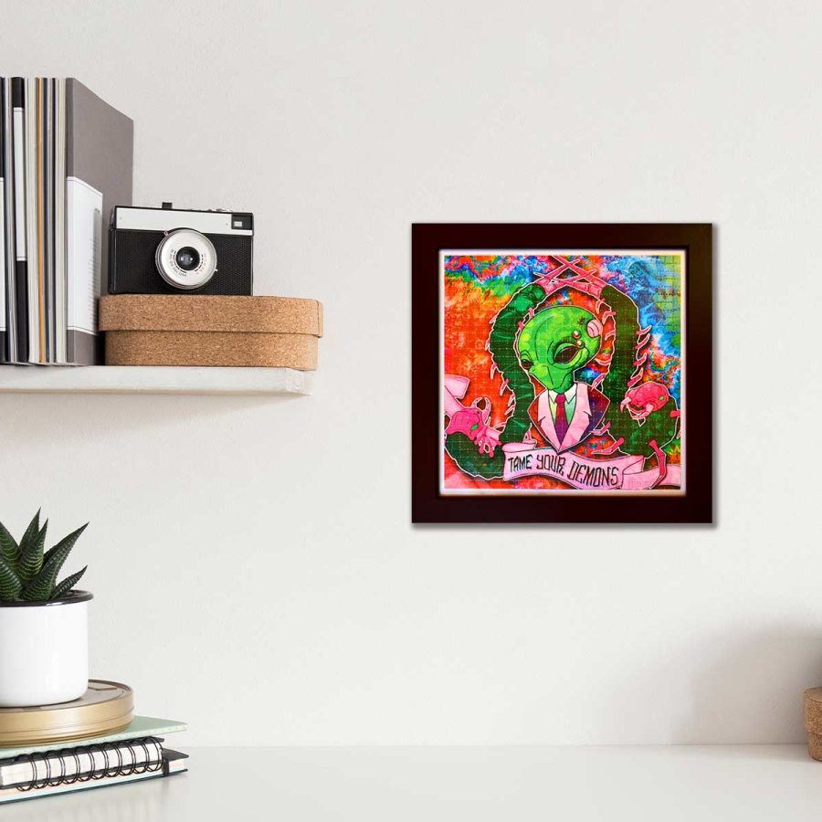 photo of a framed lsd blotter acid art print featuring psychedelic colours and an alien above a scroll that says tame your demons