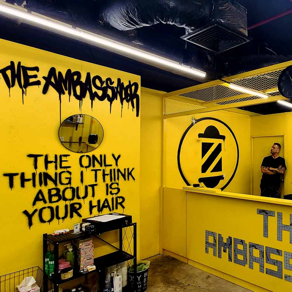 urban lettering graffiti mural before and after photos with stencil style lettering inside The Ambassador Barbershop in Bangkok by artist Vinni Kiniki