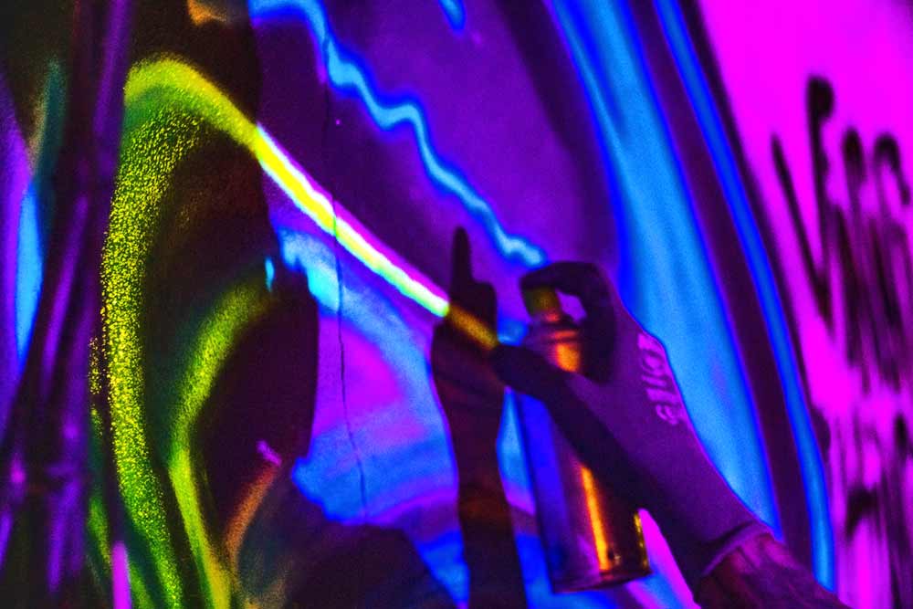 close up of black light mural painting by vinni kinki - fluorescent spray paint in progress close up
