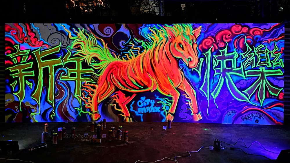 The Fire Horse black light graffiti mural glowing under ultraviolet light at Taipei Cinema Park, Ximending, revealing vibrant UV-reactive fluorescent colours.